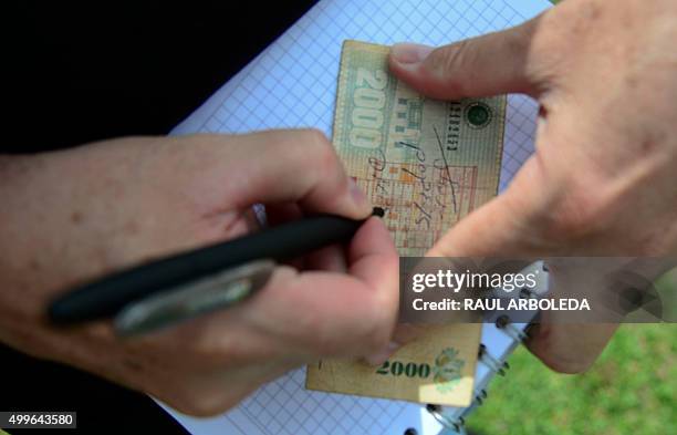 John Jairo Velasquez, A.K.A "Popeye", signs a bank note beside the tomb of Colombian drug lord Pablo Escobar at the Montesacro cemetery in Medellin,...