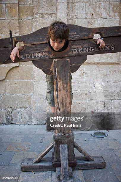 a boy trapped in a medieval torture device, mdina, malta - torture in the middle ages stock pictures, royalty-free photos & images