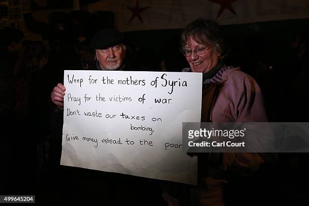 Demonstrators hold a banner as they protest against British airstrikes against Islamic State targets in Syria outside Parliament on December 2, 2015...