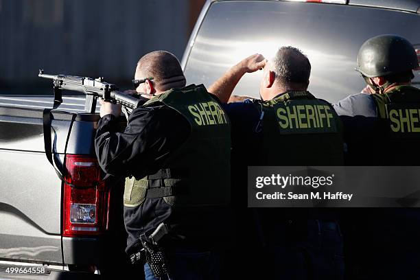 San Bernadino Sheriff officers point weapons into a neighborhood as they pursue suspects of the shooting at the Inland Regional Center on December 2,...