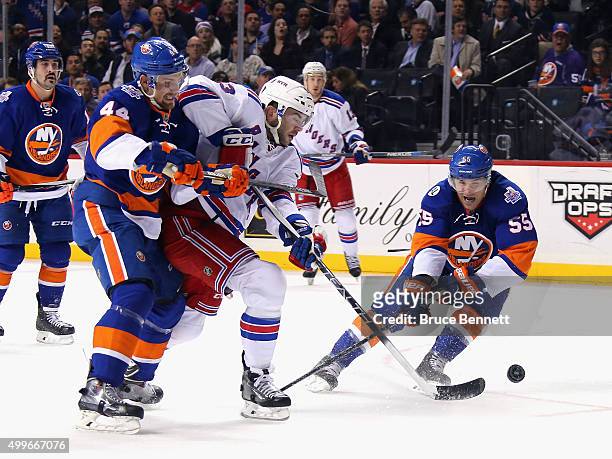 Keith Yandle of the New York Rangers gets the shot off as he is checked by Calvin de Haan and Johnny Boychuk of the New York Islanders during the...