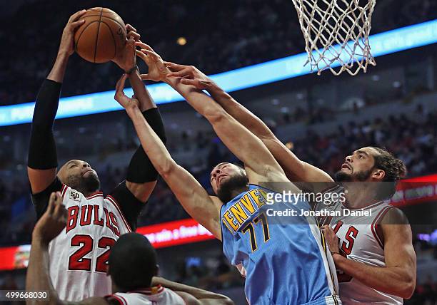 Taj Gibson of the Chicago Bulls grabs a rebound away from Joffrey Lauvergne of the Denver Nuggets as Joakim Noah applies defensive pressure at the...