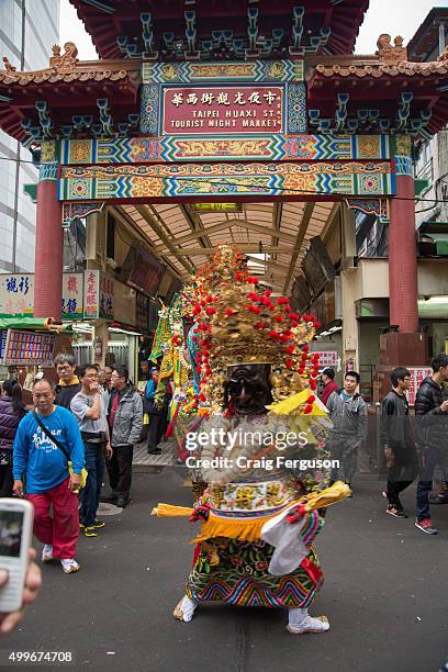Walking God's head appears outside the Huaxi St night market also known as Snake Alley. The market is famous for restaurants serving snake blood and...