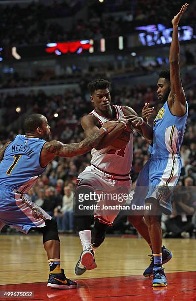 Jimmy Butler of the Chicago Bulls drives between Jameer Nelson and Will Barton of the Denver Nuggets at the United Center on December 2, 2015 in...