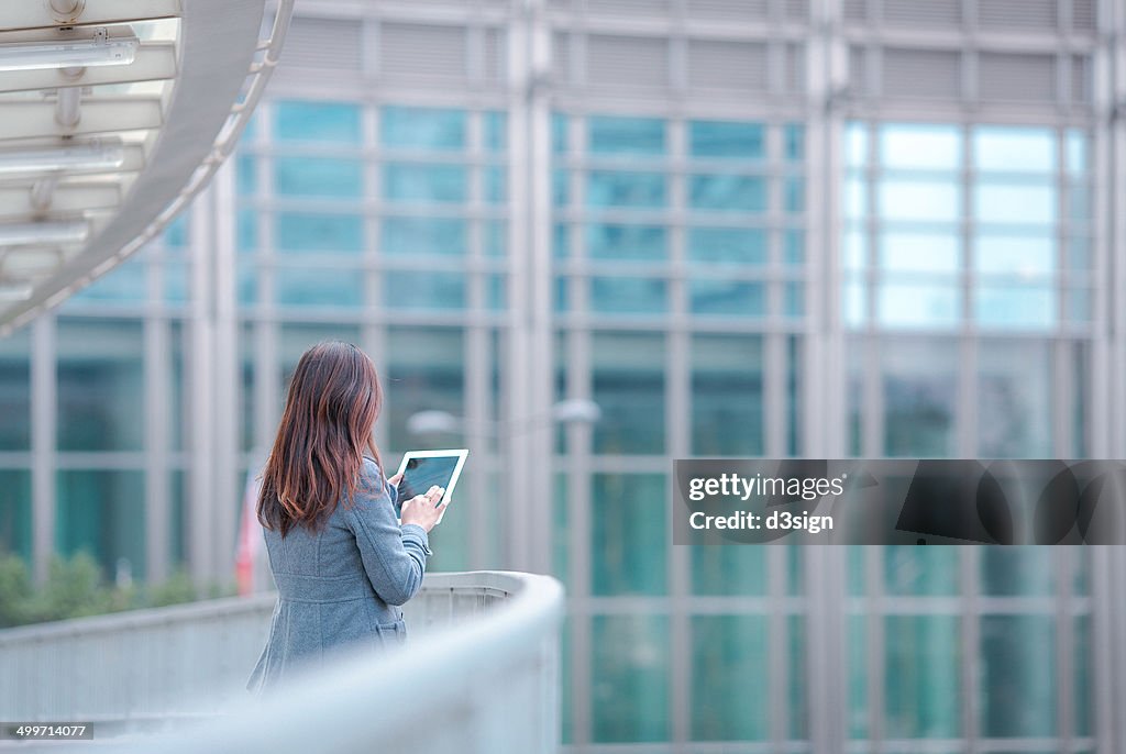 Businesswoman using tablet computer outside office