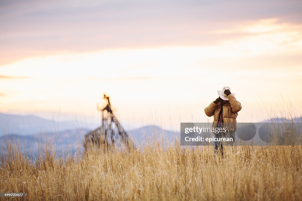 Man walking across mountain holds hat and talks on phone
