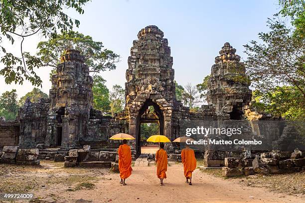 buddhist monks walking inside angkor wat temple - camboya fotografías e imágenes de stock