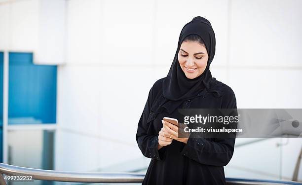 satisfecho oriente mujer de negocios mediante teléfono fuera de oficina - emirati face smile fotografías e imágenes de stock