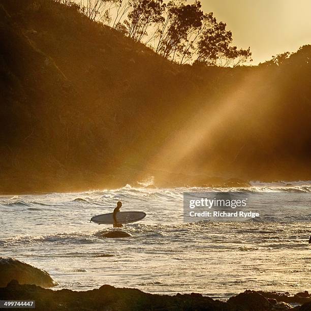 beams of sunlight shine down on a surfer - byron bay imagens e fotografias de stock