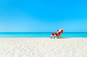 Christmas Santa Claus resting on deckchair at ocean sandy beach