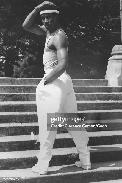 Male model wearing headband and baggy white pants posing on steps, San Francisco, California, 1980.