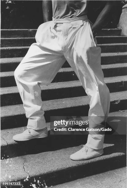 Male model wearing headband and baggy white pants posing on steps, San Francisco, California, 1980.