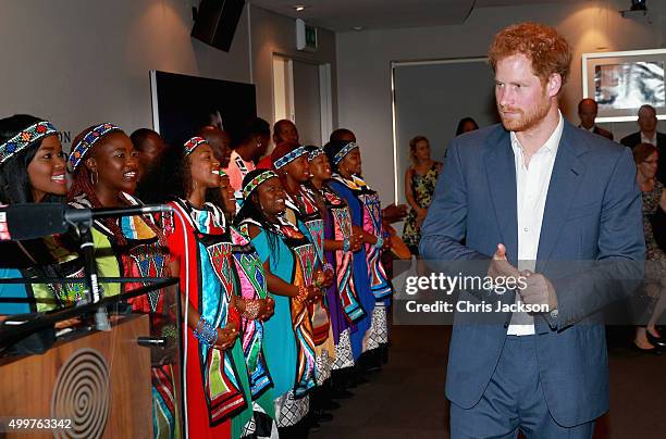 Prince Harry walks past traditional singers from Soweto at the Nelson Mandela Foundation Centre of Memory on December 3, 2015 in Johannesburg, South...