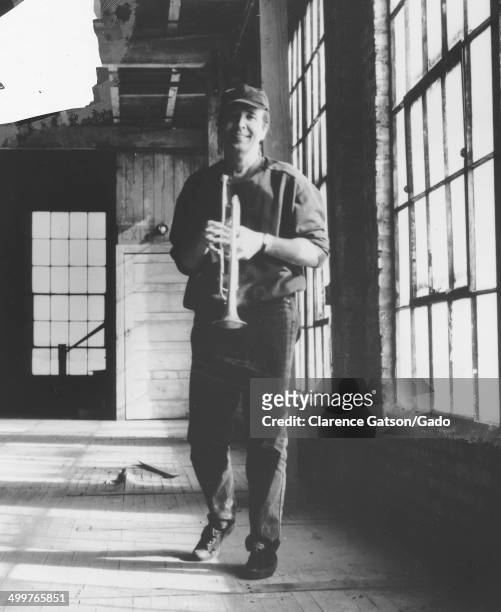 Publicity photo of Herb Alpert, with a trumpet, in an industrial building, San Francisco, California, 1980.