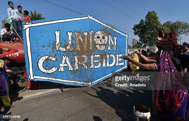 Protestor smears mud on a logo of Union Carbide, the factory at the center of the gas tragedy, as survivors and relatives of the victims take part in...