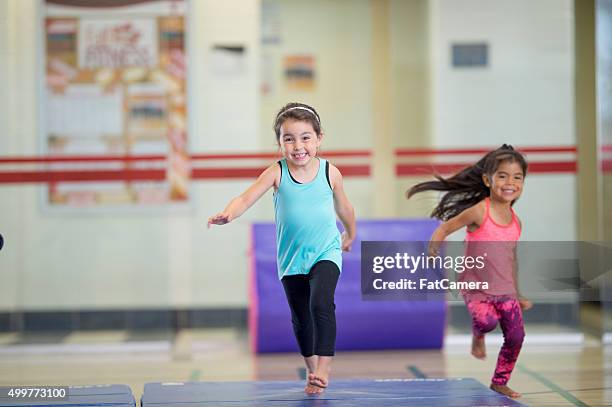 little girls running on gymnastics mats - gymnastiek stockfoto's en -beelden