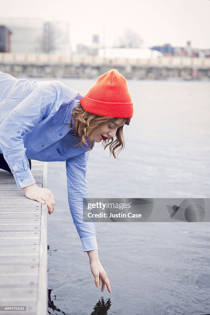 Woman touching the sea water from a pier
