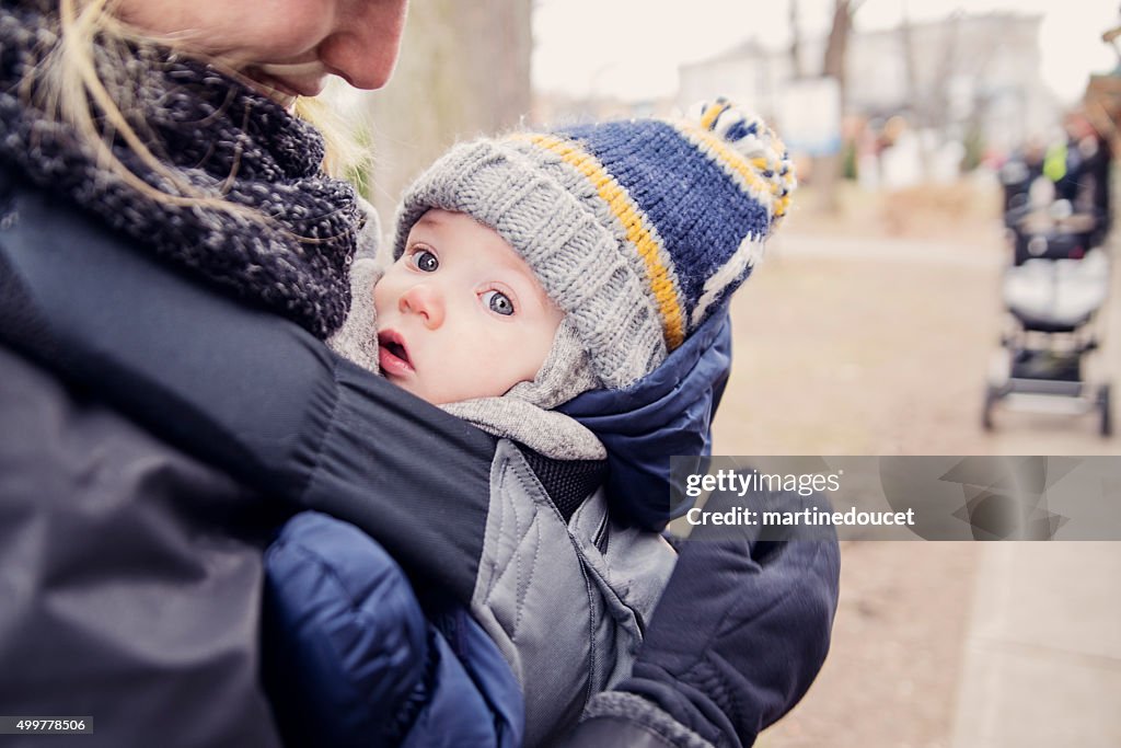 Mother with baby in carrier, outdoors in winter.