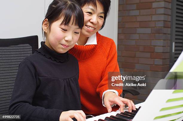 mother and daughter playing keyboard together - musikalische begleitung stock-fotos und bilder