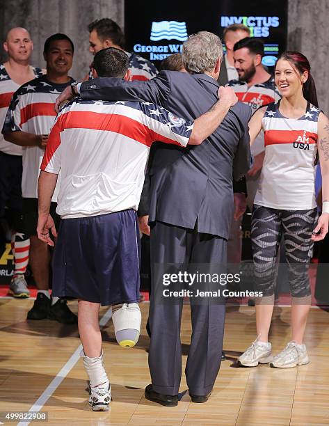 Staff Sergeant Nicholas Dadgostar hugs Former President George W. Bush as he greets Yeoman 3rd Class Kristen Esget during an event to announce a...
