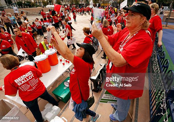 Registered nurses Patricia Sanchez, left and Amy Scott, right, take photos as the join hundreds of nurses and environmental activists that marched...