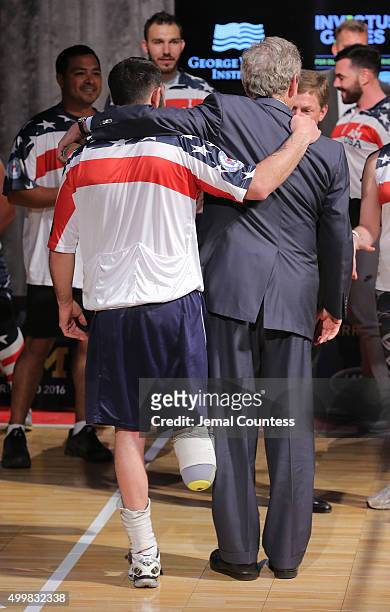 Staff Sergeant Nicholas Dadgostar hugs Former President George W. Bush as he greets Yeoman 3rd Class Kristen Esget during an event to announce a...