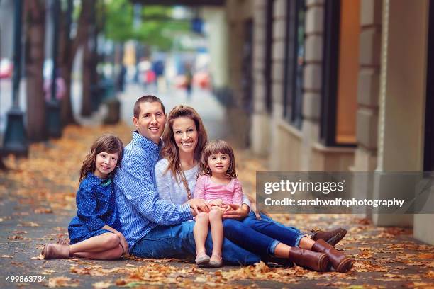 family sitting on a leaf covered sidewalk in a city - fall in seattle fotografías e imágenes de stock