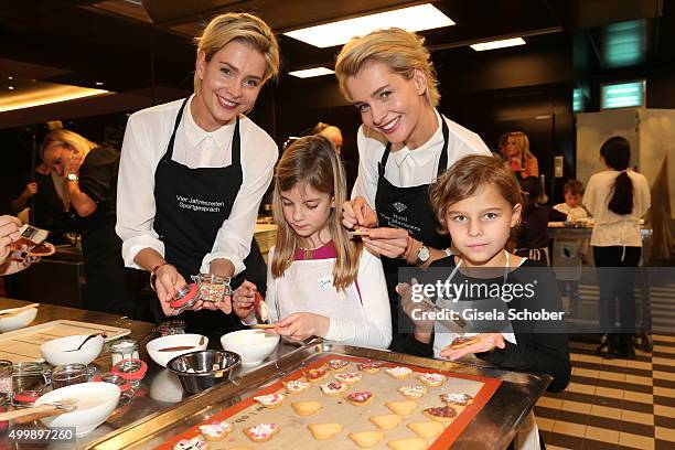 Julia Meise and her twin sister Nina Meise prepare cookies with children during the World Childhood Foundation Baking at Hotel Vier Jahreszeiten on...