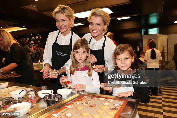 Julia Meise and her twin sister Nina Meise prepare cookies with children during the World Childhood Foundation Baking at Hotel Vier Jahreszeiten on...