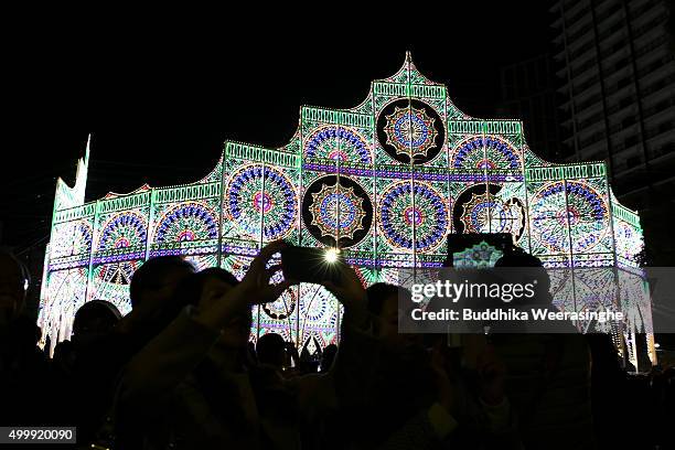 People use their smart phone and take pictures under an illuminated structure as a part of the 21th Kobe Luminarie on December 4, 2015 in Kobe,...