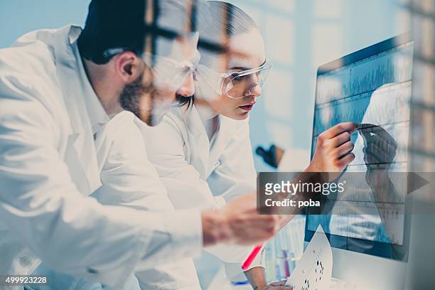 wissenschaftler auf der suche auf ein dna sequence auf dem monitor - medical research stock-fotos und bilder