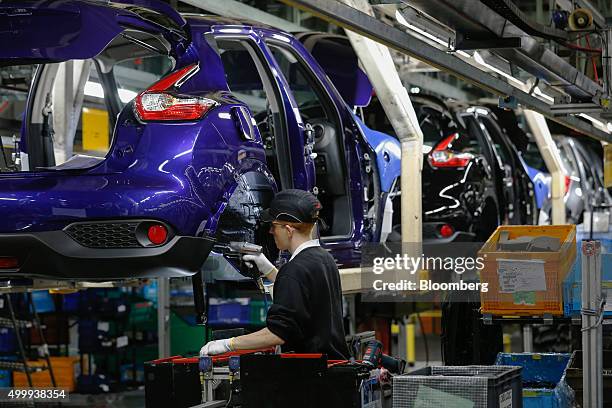 An employee drills into the wheel arch of a Nissan Juke on the production line at the Nissan Motor Co. Production plant in Sunderland, U.K., on...