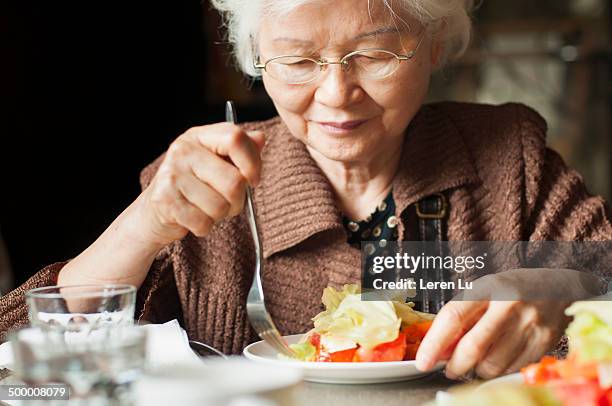 old lady eating salad gracefully - senior adult eating stock pictures, royalty-free photos & images