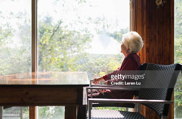 old lady sitting and looking outward - solitudine foto e immagini stock