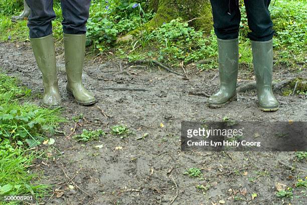 two friends in rubber boots on muddy path - lyn holly coorg stockfoto's en -beelden