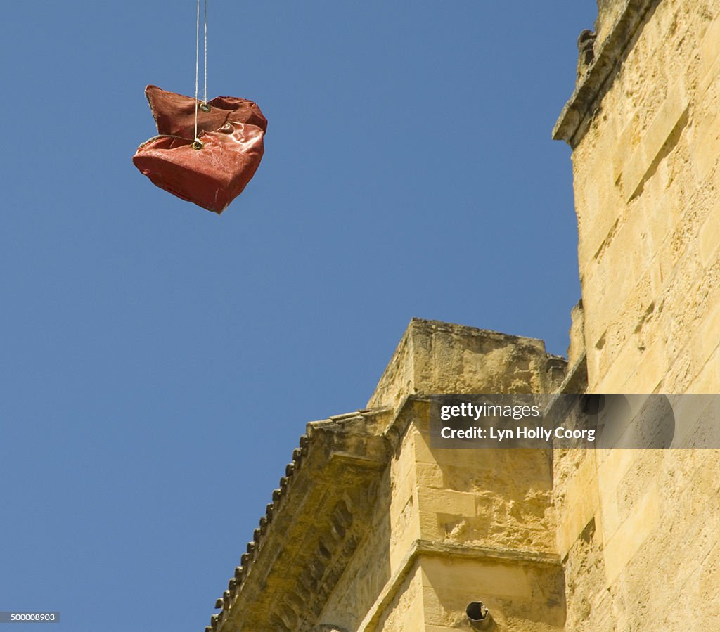 Red hearts hanging on wires by stone building