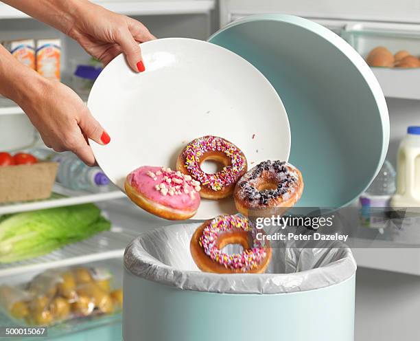 dieter throwing away donuts - lebensmittel müll stock-fotos und bilder