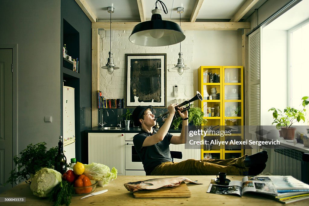 Caucasian man playing trumpet in kitchen