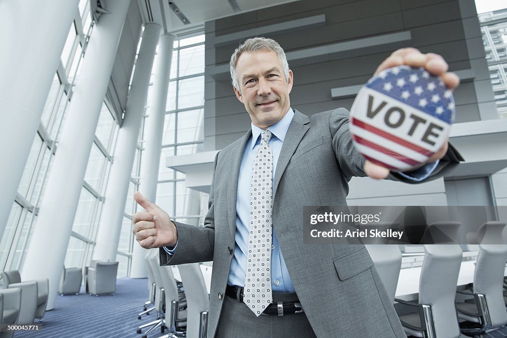 Caucasian businessman holding Vote' button