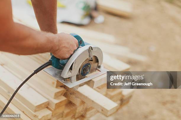 caucasian construction worker sawing wood planks - elektrisch gereedschap stockfoto's en -beelden