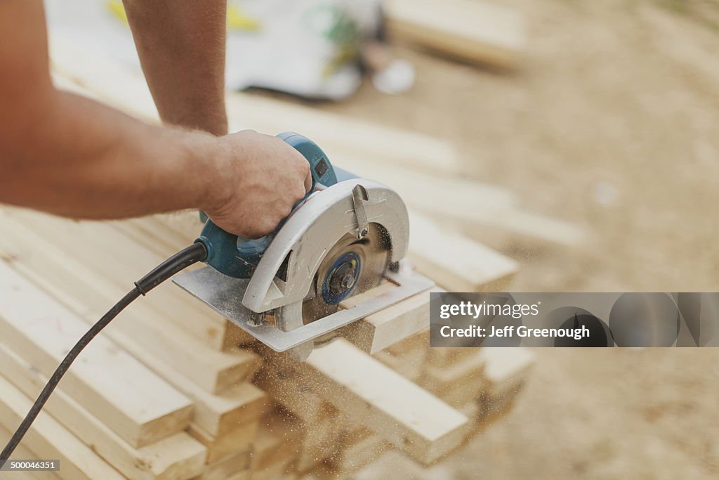 Caucasian construction worker sawing wood planks