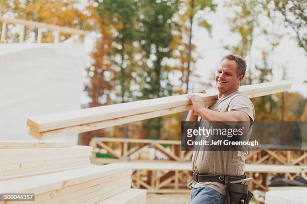 caucasian construction worker carrying wood planks - carry foundation stock-fotos und bilder