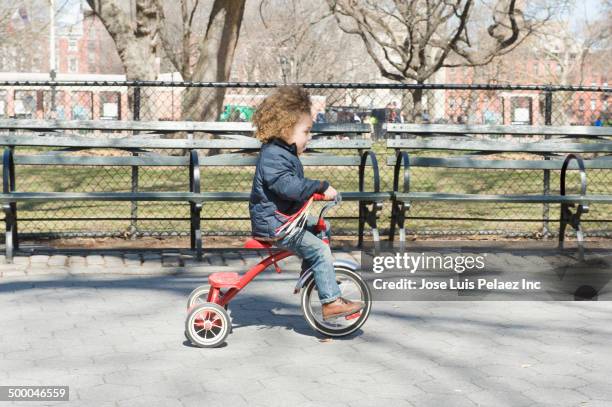 mixed race boy riding tricycle in park - tricycle stock pictures, royalty-free photos & images