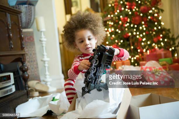 mixed race boy opening christmas presents - christmas toys stock pictures, royalty-free photos & images
