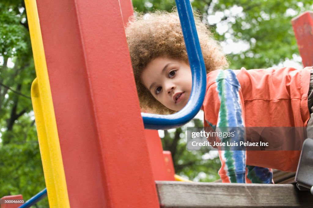 Mixed race boy playing on playground