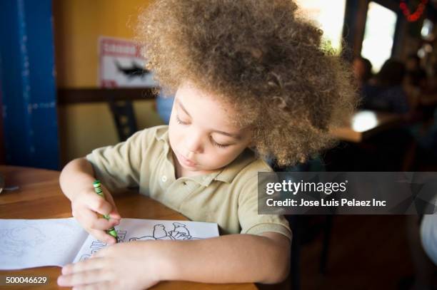 mixed race boy coloring at desk - malbuch stock-fotos und bilder