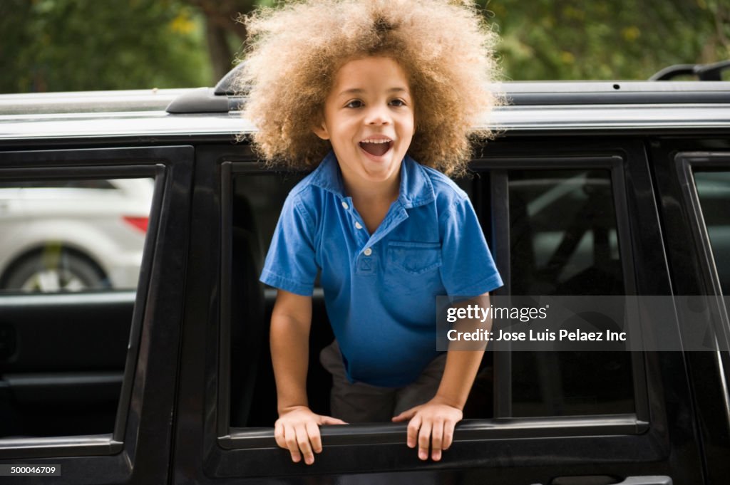 Mixed race boy leaning out car window