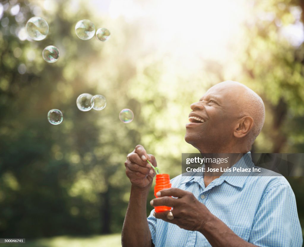 Senior Black man blowing bubbles outdoors