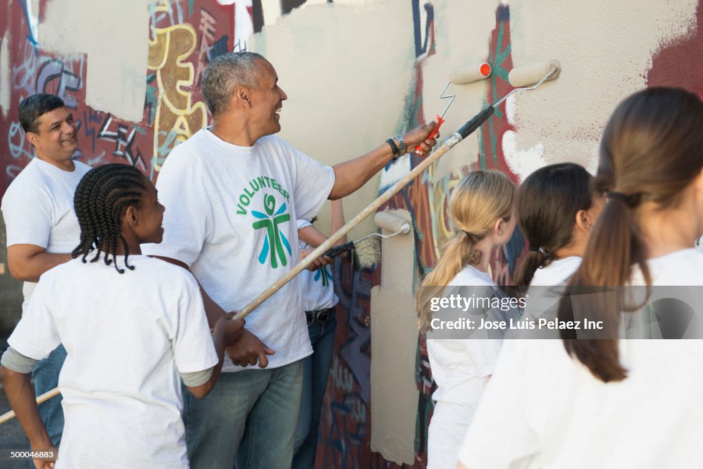 Volunteers painting over graffiti wall