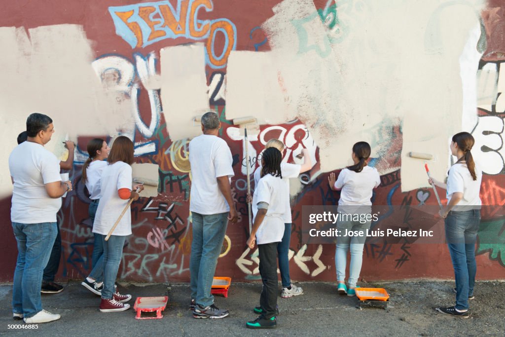 Volunteers painting over graffiti wall